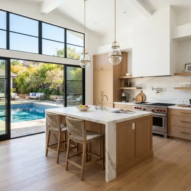 A modern renovated kitchen with warm wood cabinets and a pool visible outside
